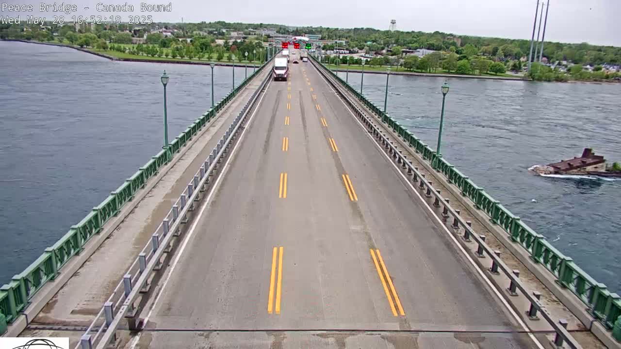 A bridge over water on an overcast day shows a few vehicles traveling toward the camera.