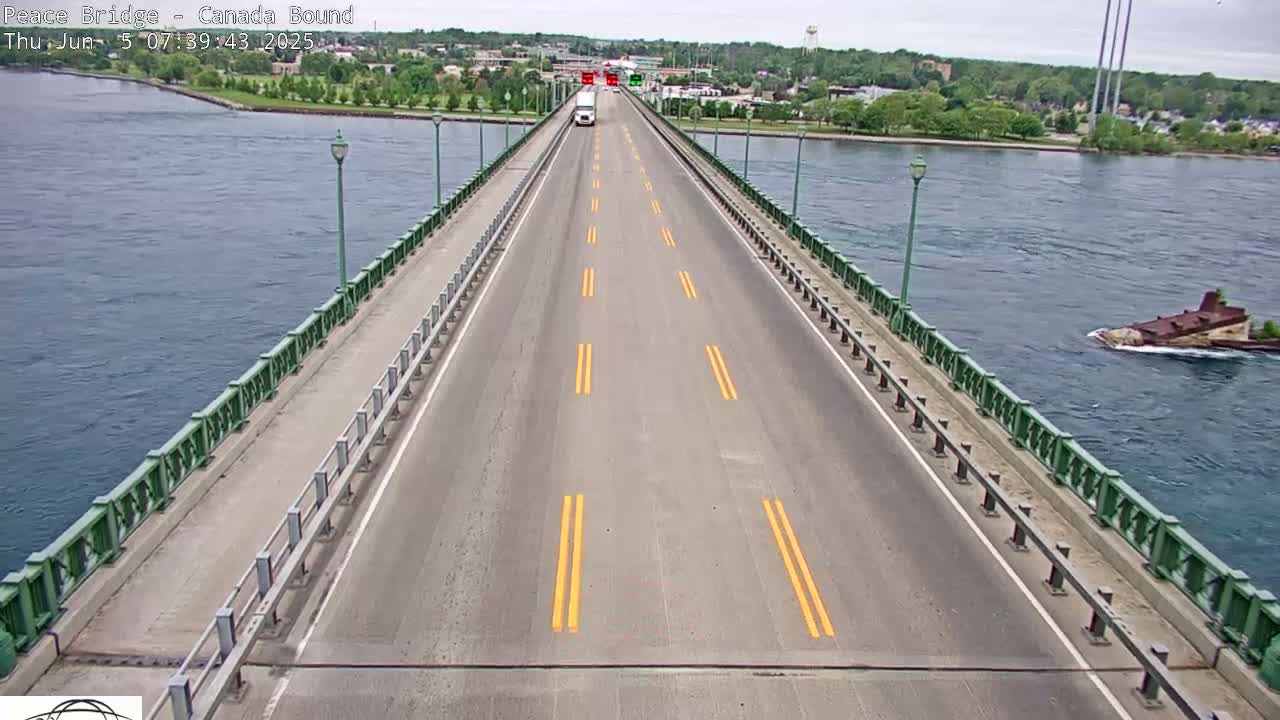 A long, two-lane bridge stretches over a body of water on an overcast day, with a single vehicle visible in the distance.