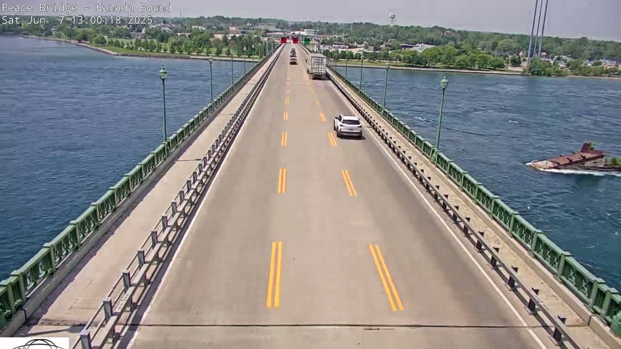 A bridge spans a body of water on a sunny day, with several vehicles traveling along the road.