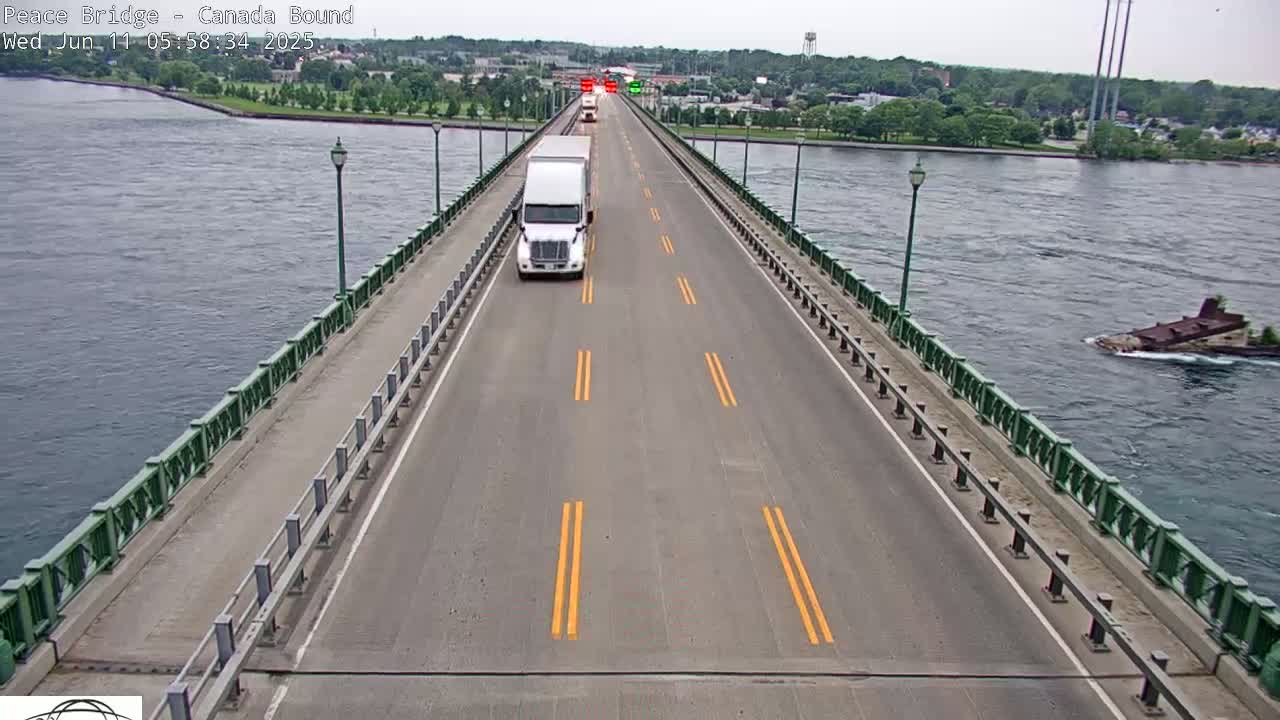 A bridge over a body of water on an overcast day with several vehicles traveling on the road.