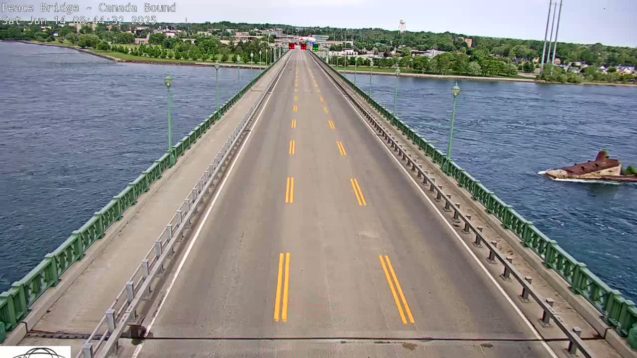 A mostly empty highway spans a bridge over a calm body of water on a partly sunny day.