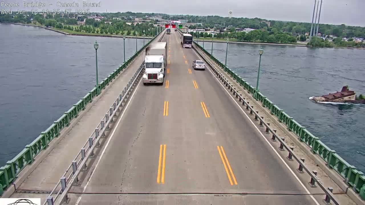 A bridge spans a body of water on an overcast day, with several vehicles traveling on the road.