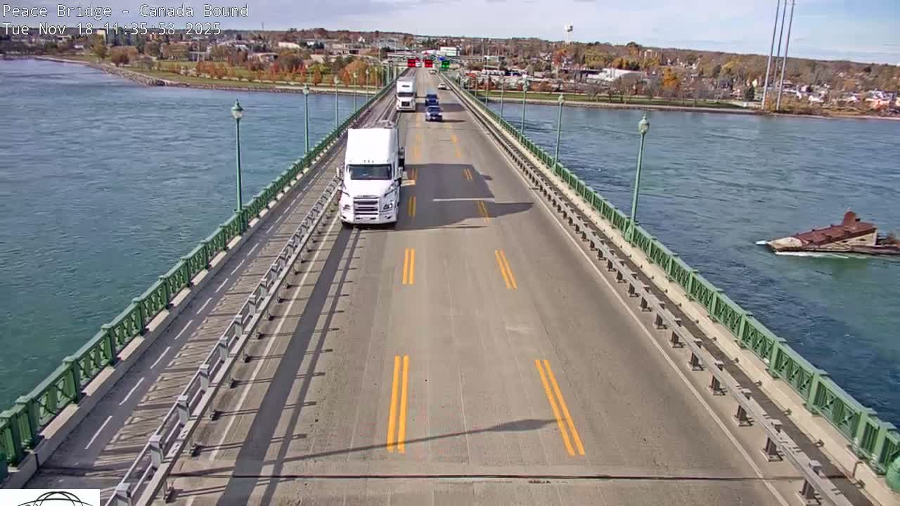 A mostly empty roadway on a bridge at night, illuminated by streetlights, overlooks dark water.