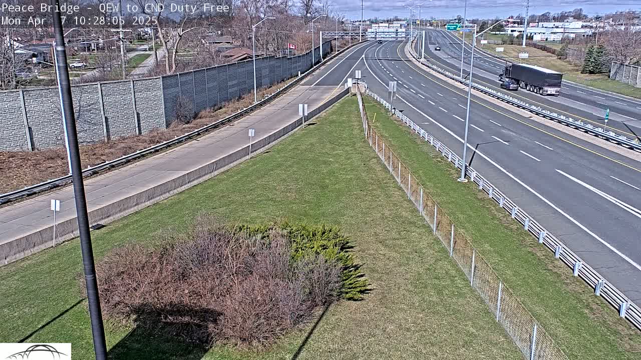 A highway merges onto a larger highway on a sunny day with a few vehicles visible.
