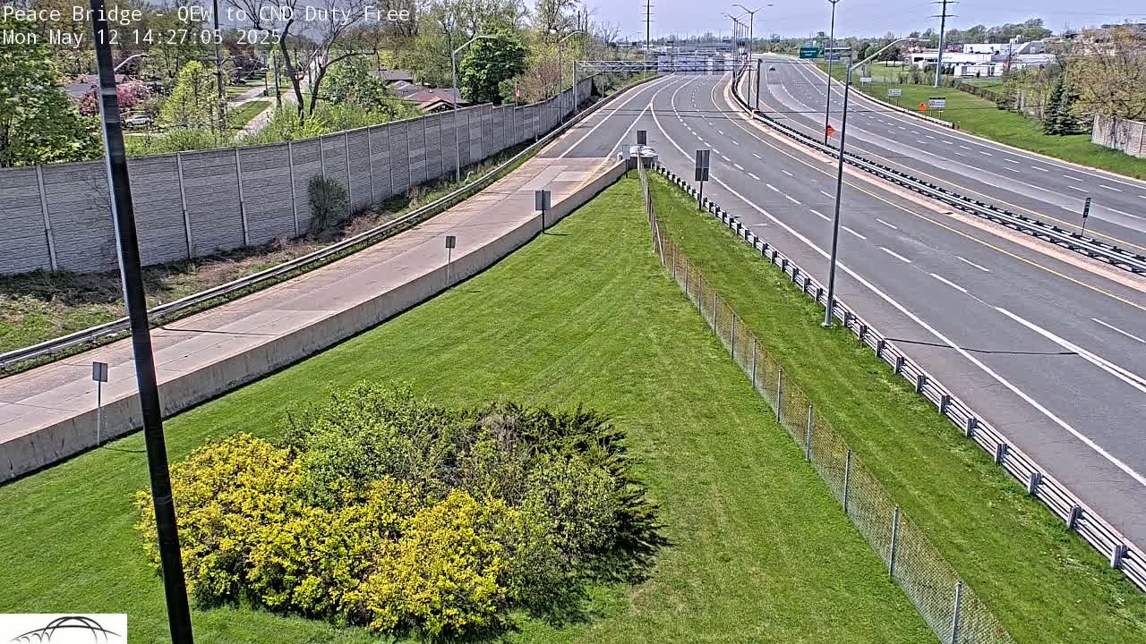 A mostly empty highway with a grassy median and a concrete barrier on a sunny day.