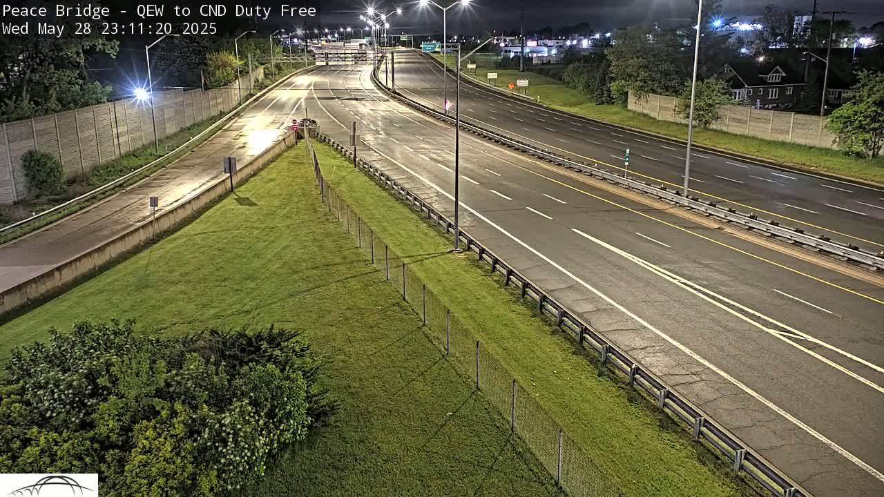 A nighttime view of a multi-lane highway with a grassy median, under mostly clear skies.