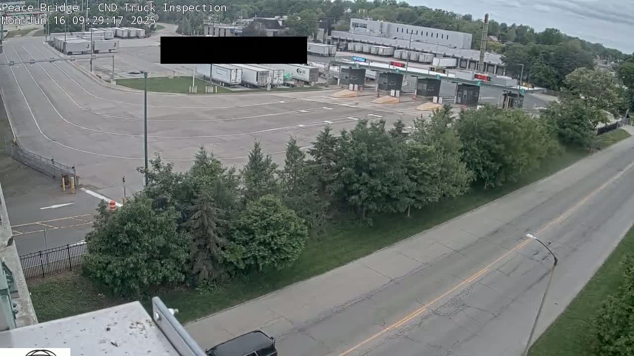 A truck inspection station with several semi-trucks parked nearby on an overcast day.
