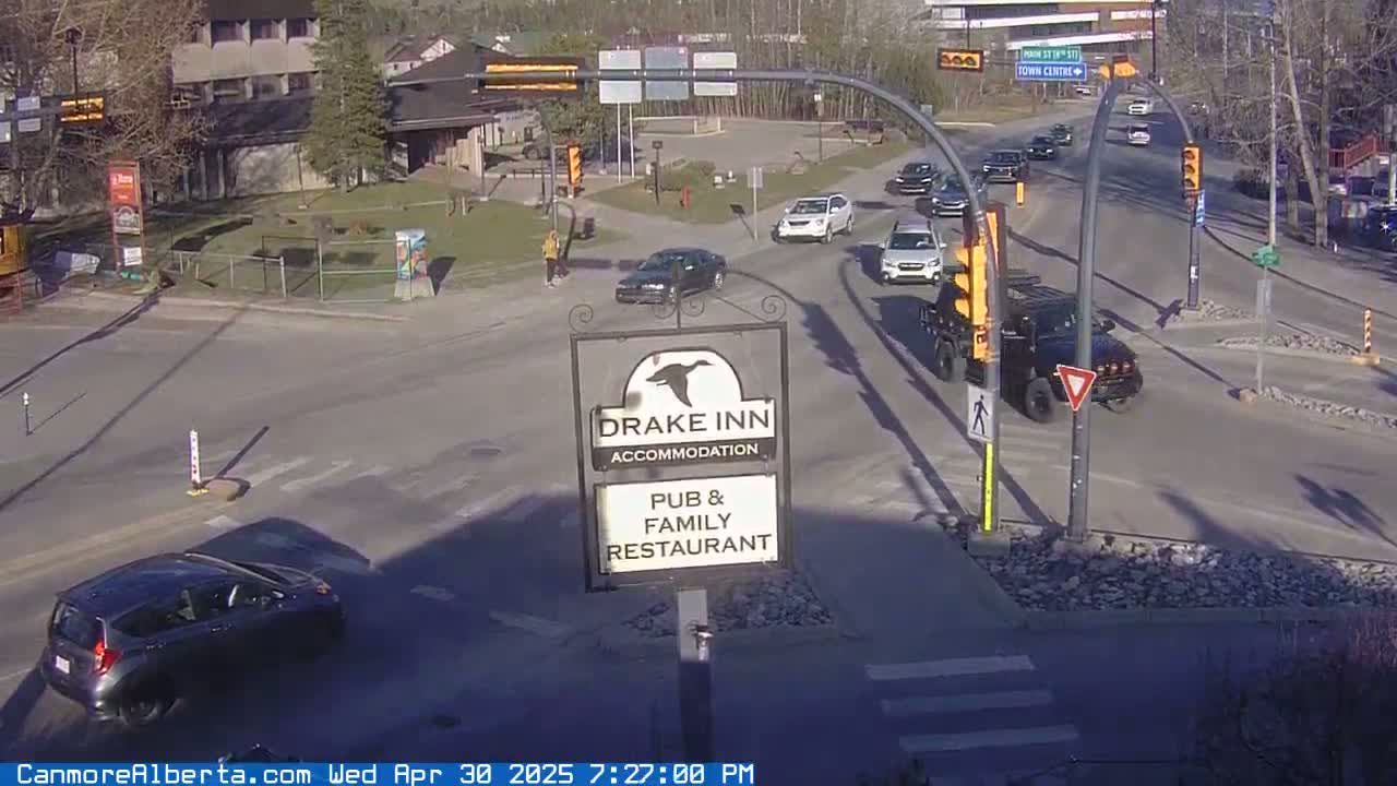 A sunny day shows a street intersection with several vehicles and a Drake Inn sign.