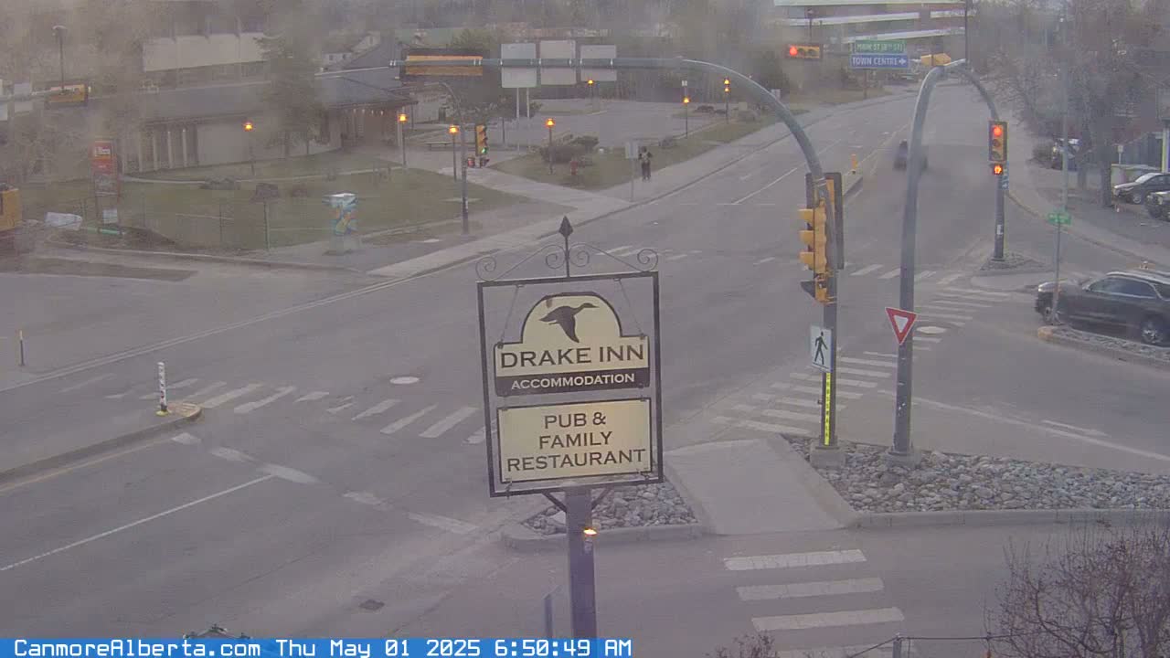 A hazy overcast scene shows a street intersection with a Drake Inn sign, traffic lights, and a few vehicles.