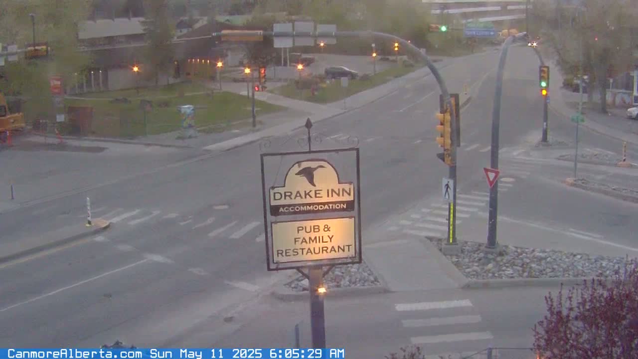 A mostly empty road intersection with traffic lights and a Drake Inn pub and restaurant sign is visible on an overcast day.