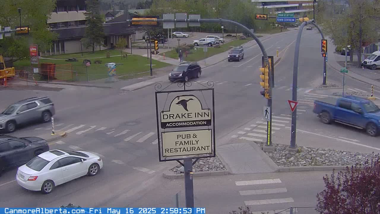 Several vehicles are navigating a street intersection on an overcast day, with a Drake Inn sign prominently displayed.