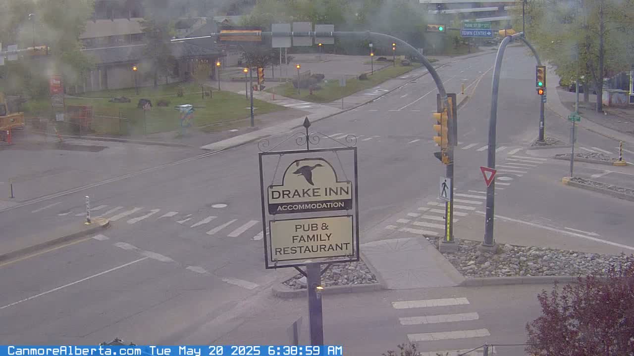 A hazy, overcast view of a road intersection with a Drake Inn pub and family restaurant sign in the foreground.