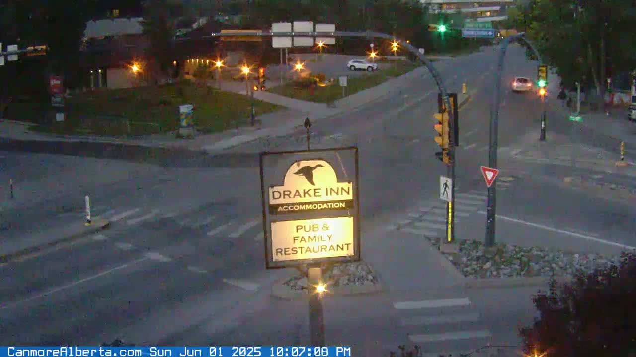 A Drake Inn pub and family restaurant sign is visible at a dimly lit intersection with a few cars, under a twilight sky.