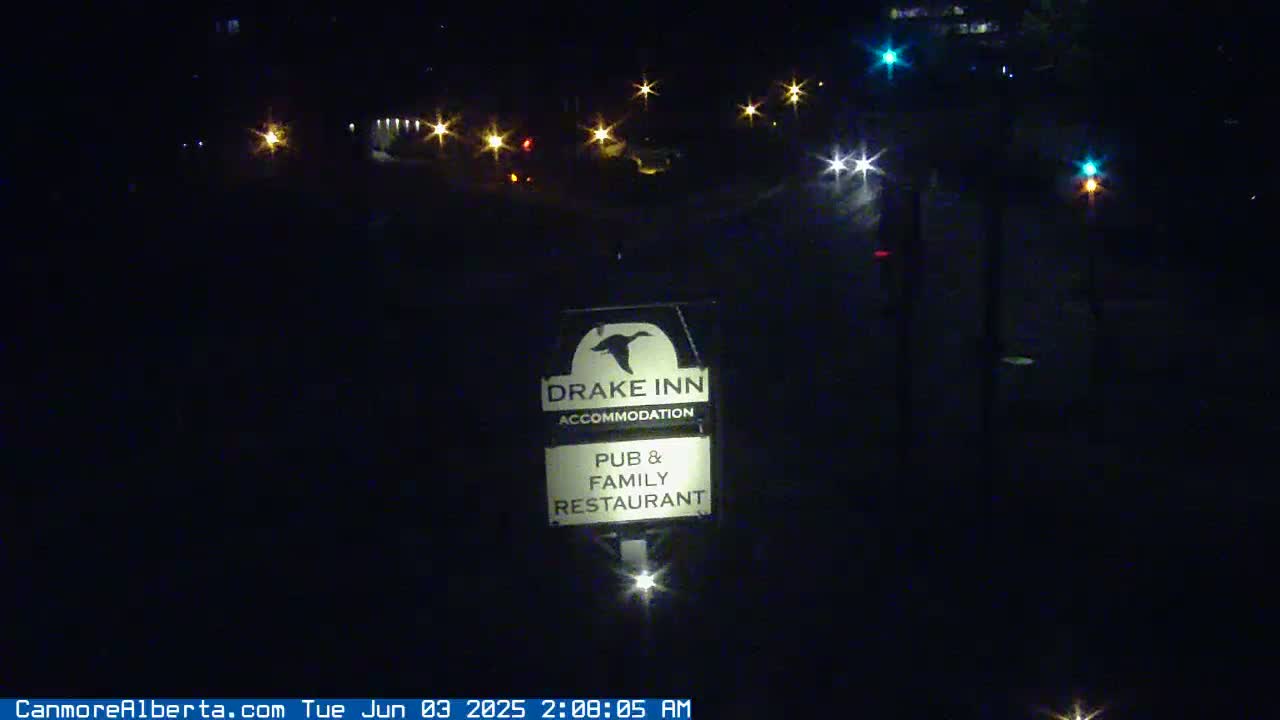 A nighttime view shows a Drake Inn sign illuminated, with distant lights visible in the dark background.