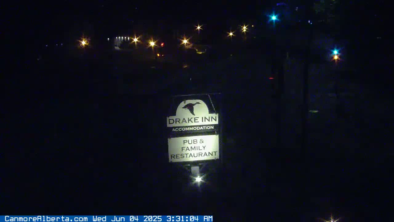 A nighttime view of a Drake Inn sign, illuminated by streetlights, indicates the inn offers accommodation, a pub, and a family restaurant.