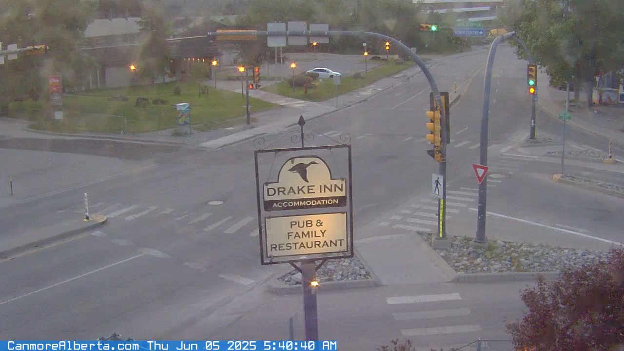 A slightly hazy view of a road intersection with traffic lights and a Drake Inn pub and family restaurant sign.