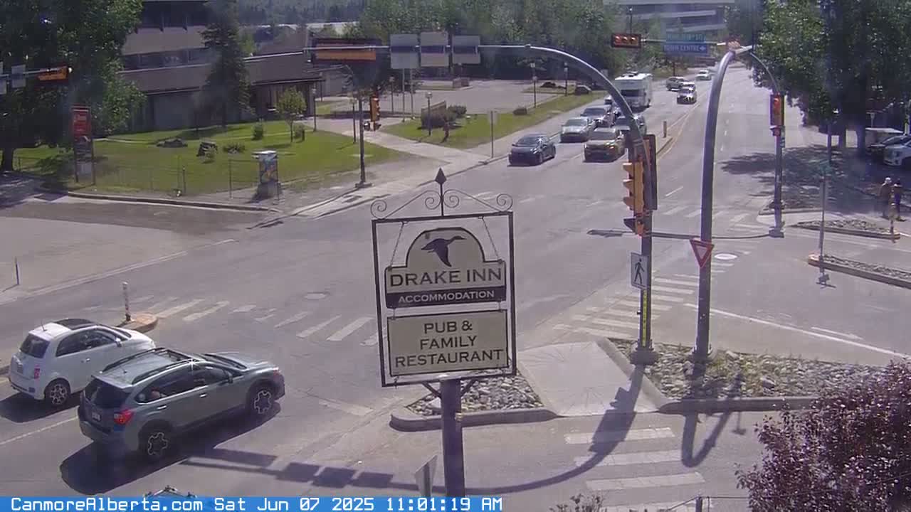 A sunny day shows a street intersection with several cars and a Drake Inn sign.