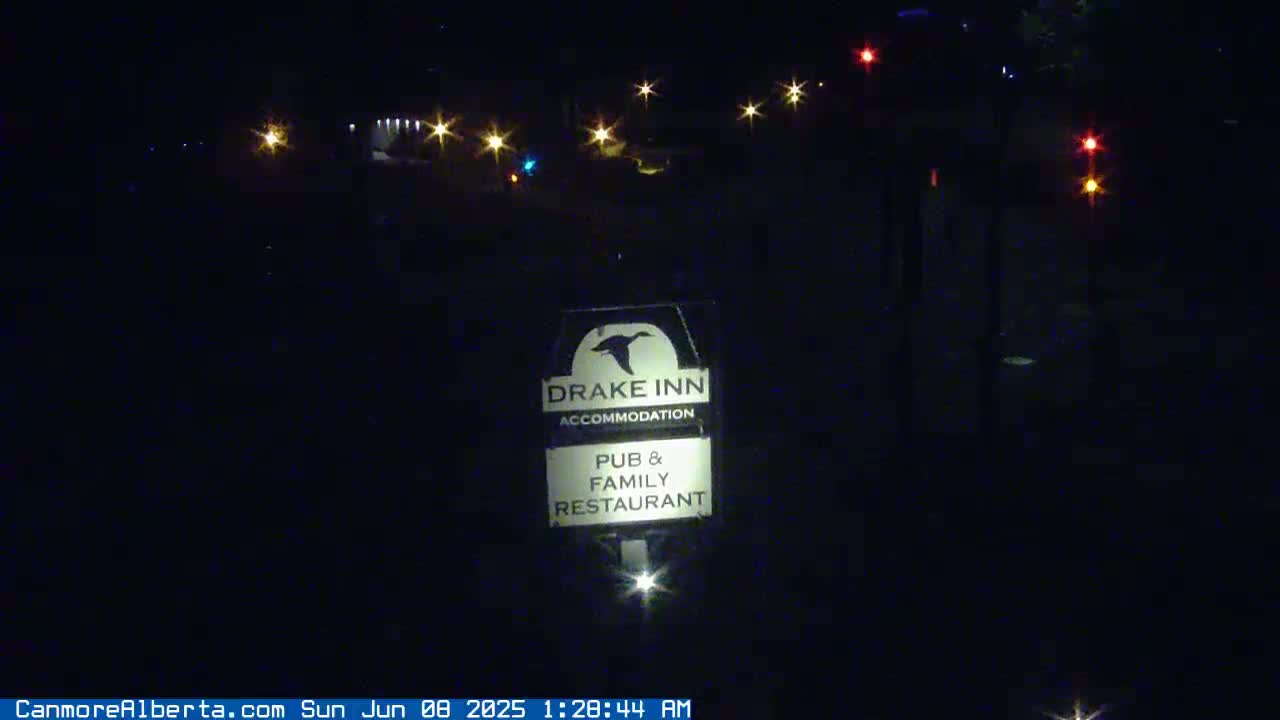 A nighttime image shows a Drake Inn sign illuminated in front of a dark background with distant lights.