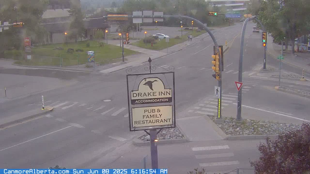 A street intersection with a Drake Inn sign, a few cars, and overcast conditions.