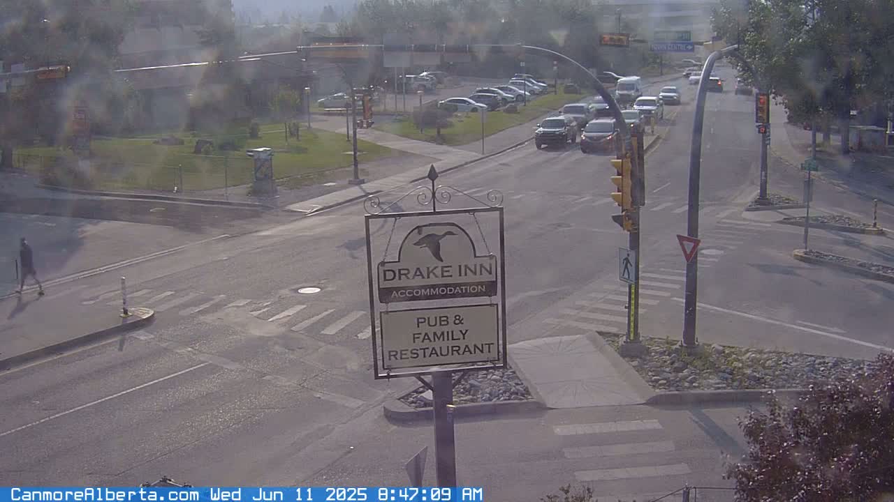 A hazy view of a street intersection with several cars, a pedestrian, and a Drake Inn sign, indicating a pub and family restaurant.