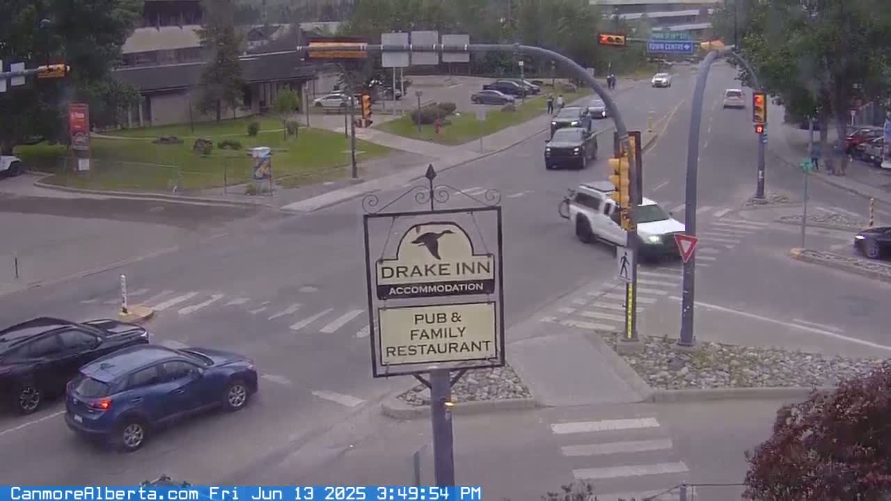 A street intersection with several vehicles, a Drake Inn sign, and overcast weather.