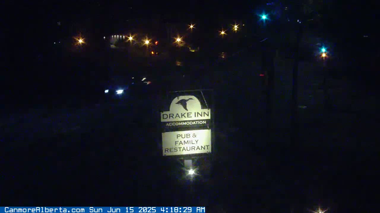A nighttime image shows a Drake Inn sign illuminated, with blurry vehicles and distant lights visible in the dark.