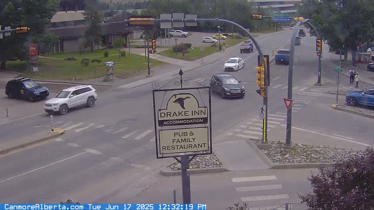 A mostly sunny, overcast day shows a road intersection with several cars, a crosswalk, and a Drake Inn sign.