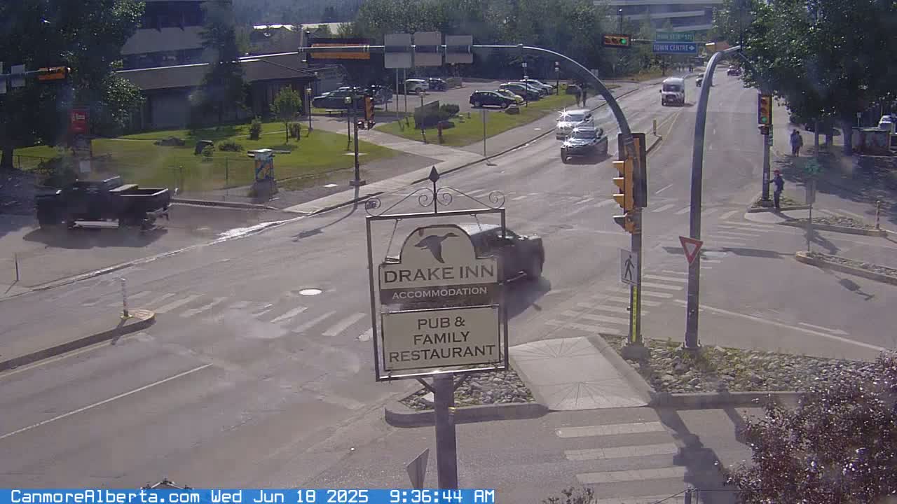 A sunny street scene shows a Drake Inn sign, several cars at a traffic intersection, and a pickup truck parked nearby.