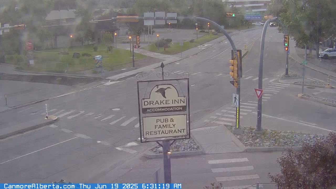 A hazy, overcast view of a street intersection with a Drake Inn pub and family restaurant sign in the foreground.