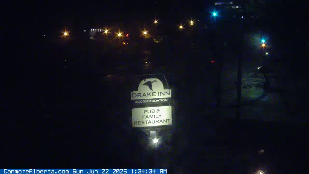 A nighttime view of a Drake Inn sign, illuminated by nearby lights, shows a pub and family restaurant in the dark.