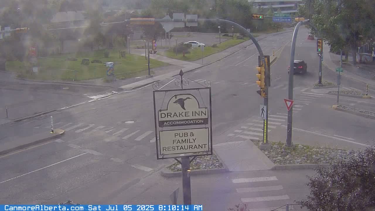 A street intersection with a Drake Inn sign shows a partly cloudy day with several vehicles at a crossroads.