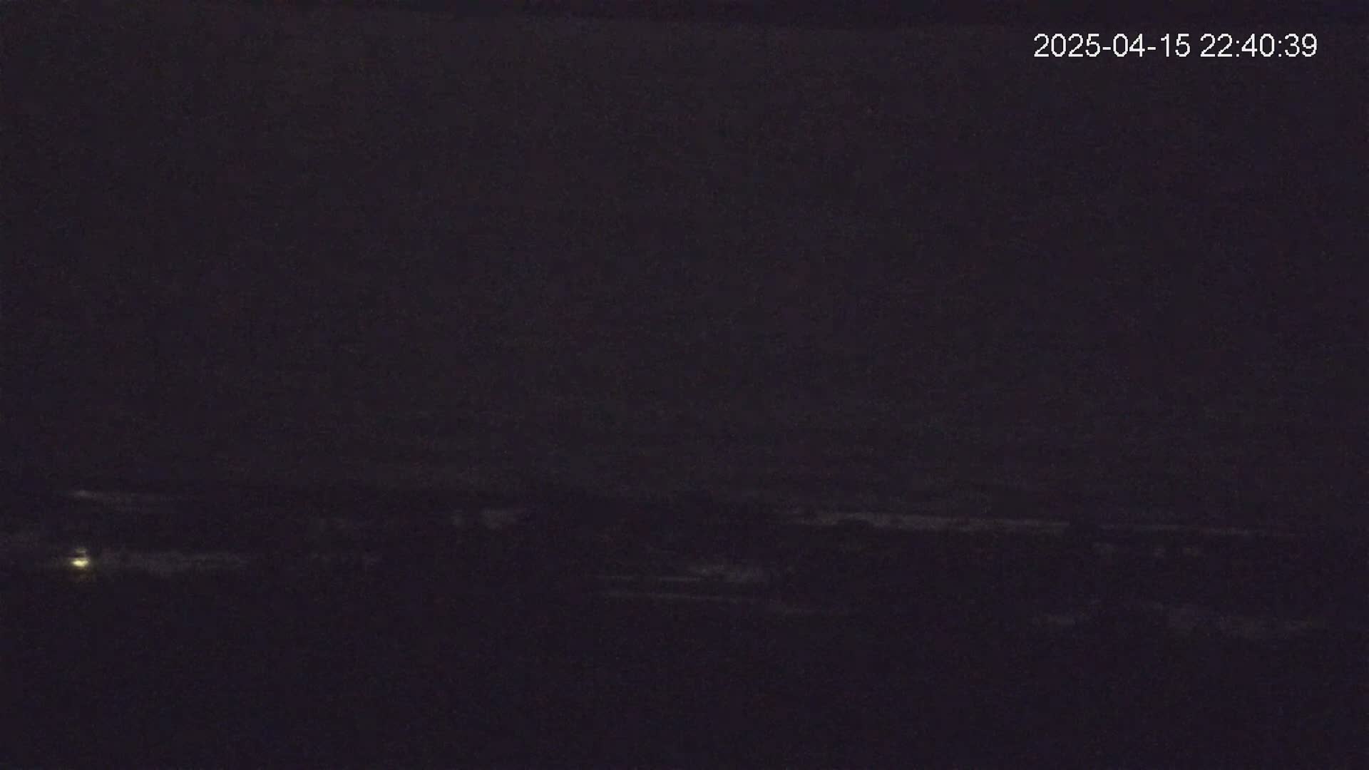 A dark, nighttime landscape is visible, showing a faintly illuminated horizon line.