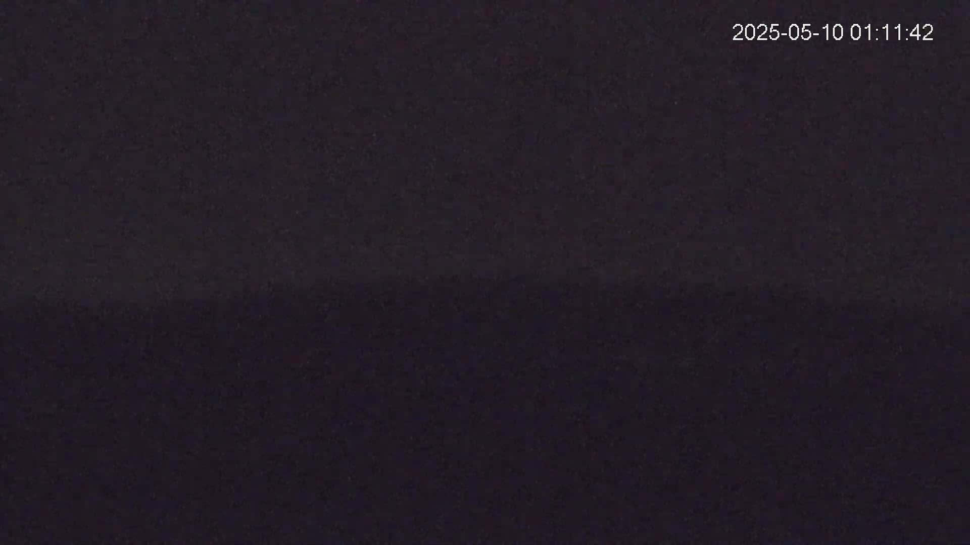 A dark, possibly nighttime, image shows a mostly uniform, dark gray or black surface.
