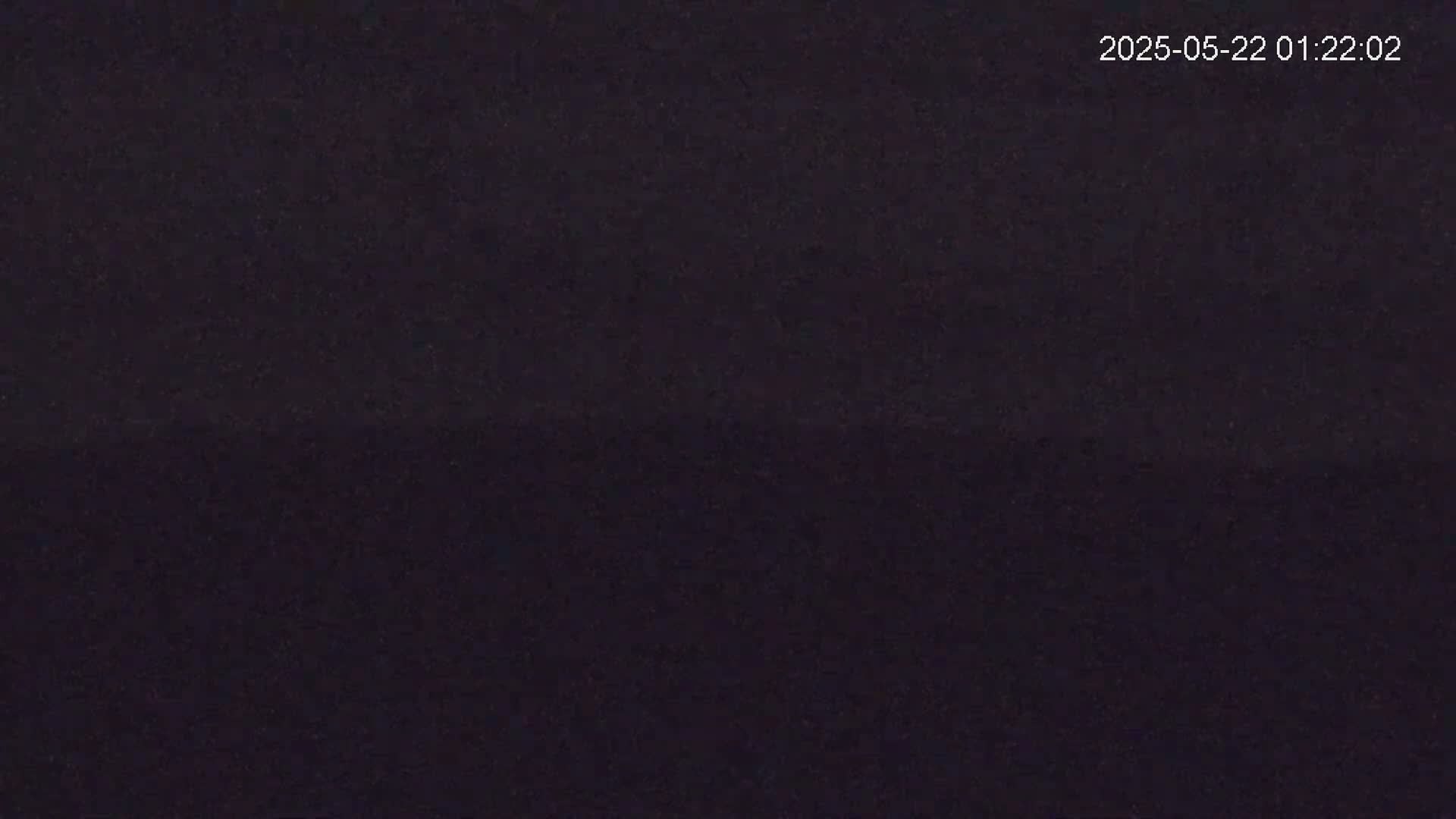 A dark, possibly nighttime, image shows a uniformly dark surface with subtle variations in shading.