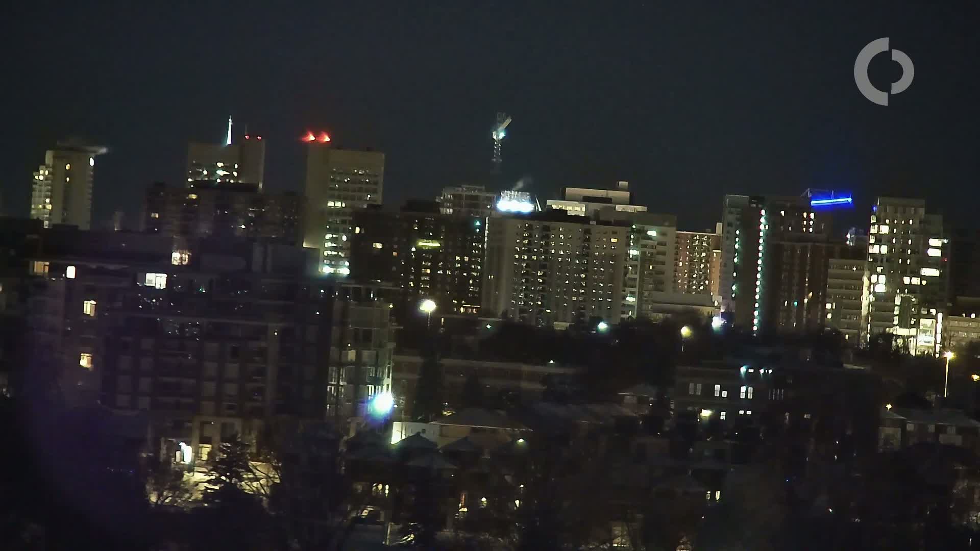 A nighttime cityscape of illuminated buildings under a dark sky.