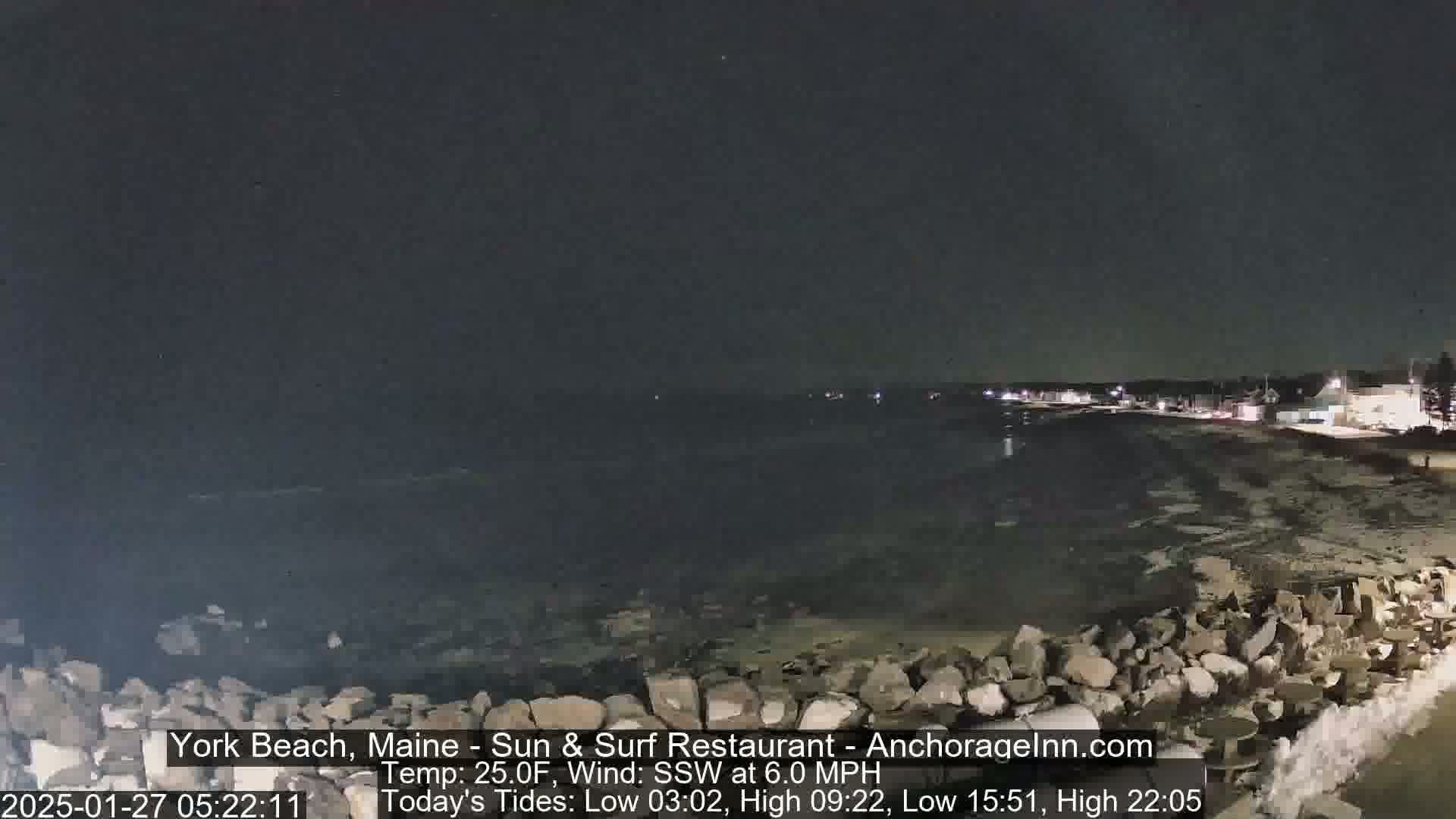 A nighttime view of a rocky shoreline with a dark ocean under a clear sky.