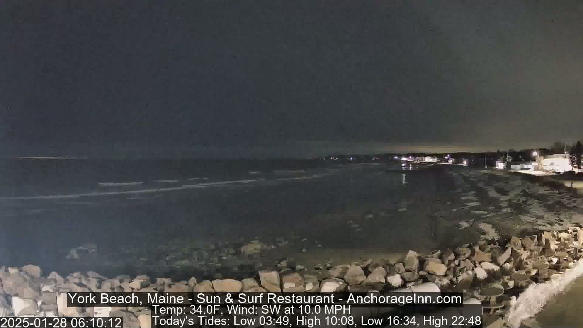 A nighttime view of a rocky shoreline and dark ocean under a mostly clear sky, with a southwest wind.