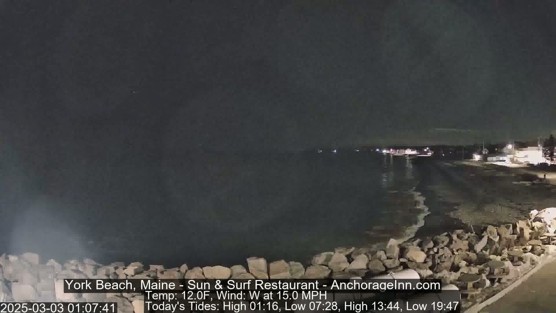A nighttime view of a rocky shoreline and dark ocean under a clear, dark sky with a 15 mph west wind.