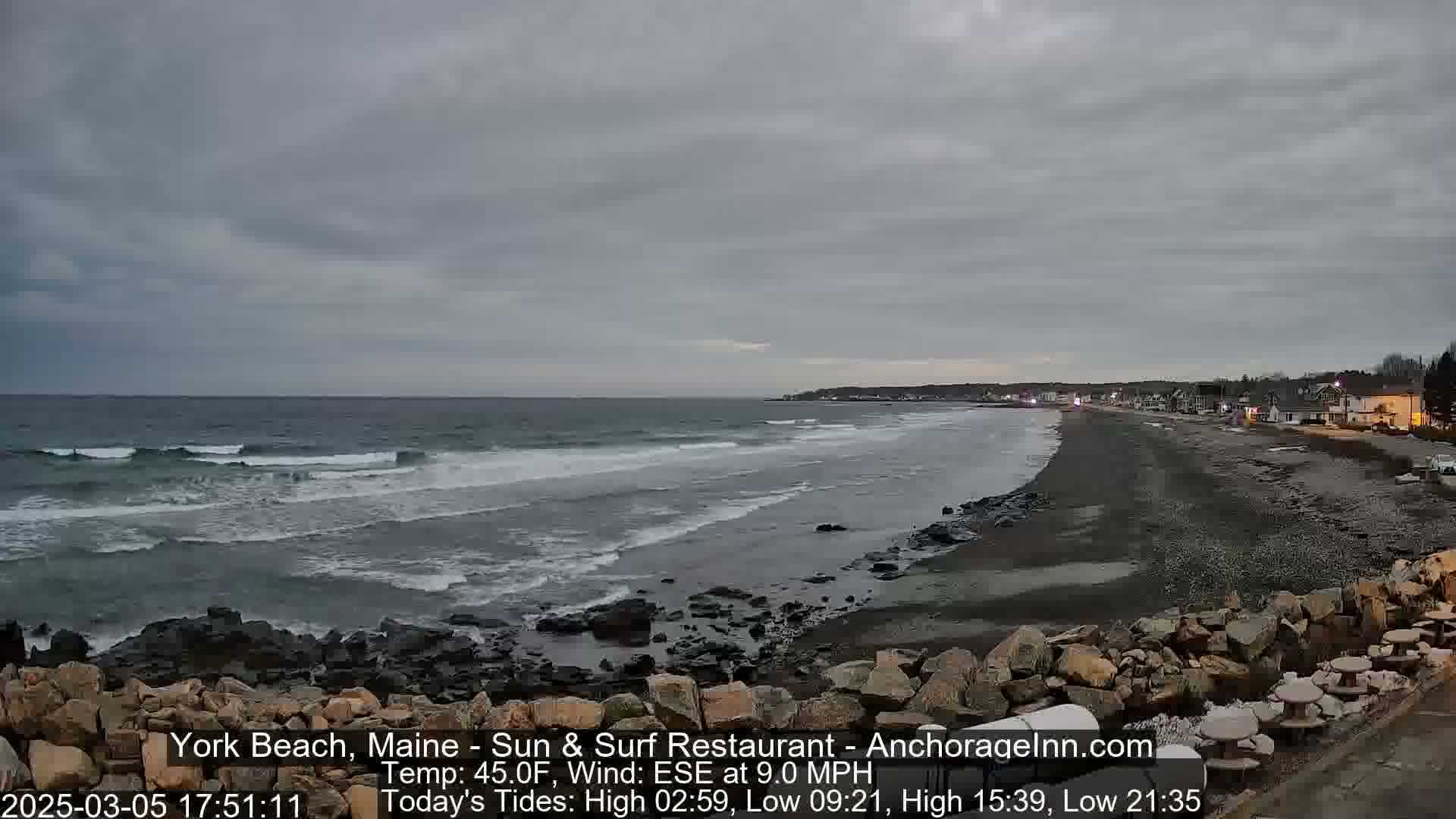 A rocky beach with a calm, gray sea under an overcast sky.