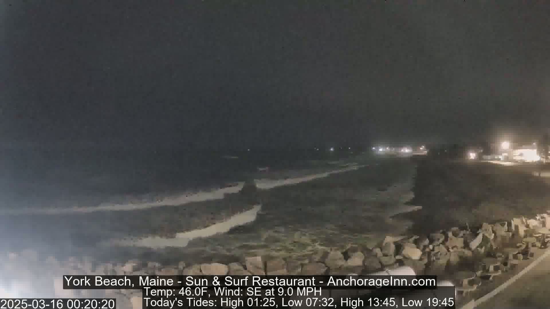 A nighttime view of a rocky shoreline with dark, choppy water under a dark sky, with a gentle southeast wind.
