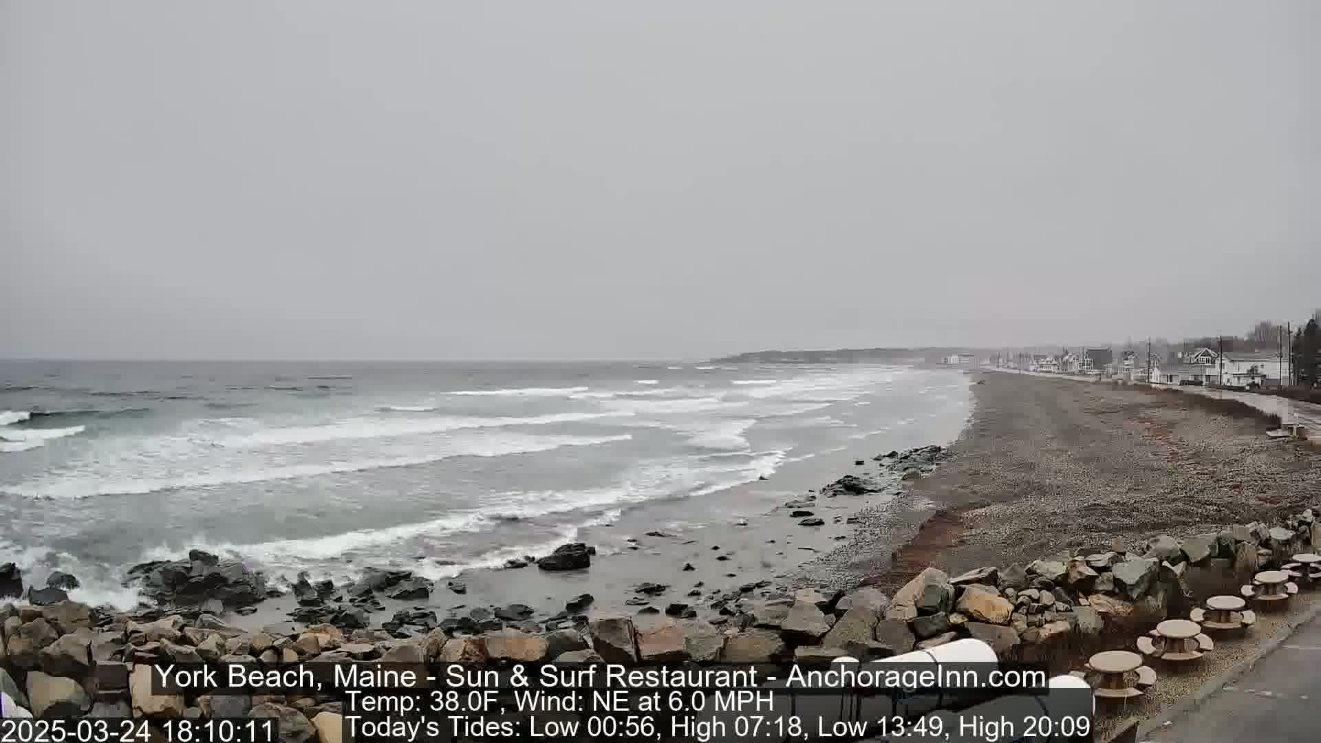 A rocky beach with gray, choppy waves under an overcast sky.