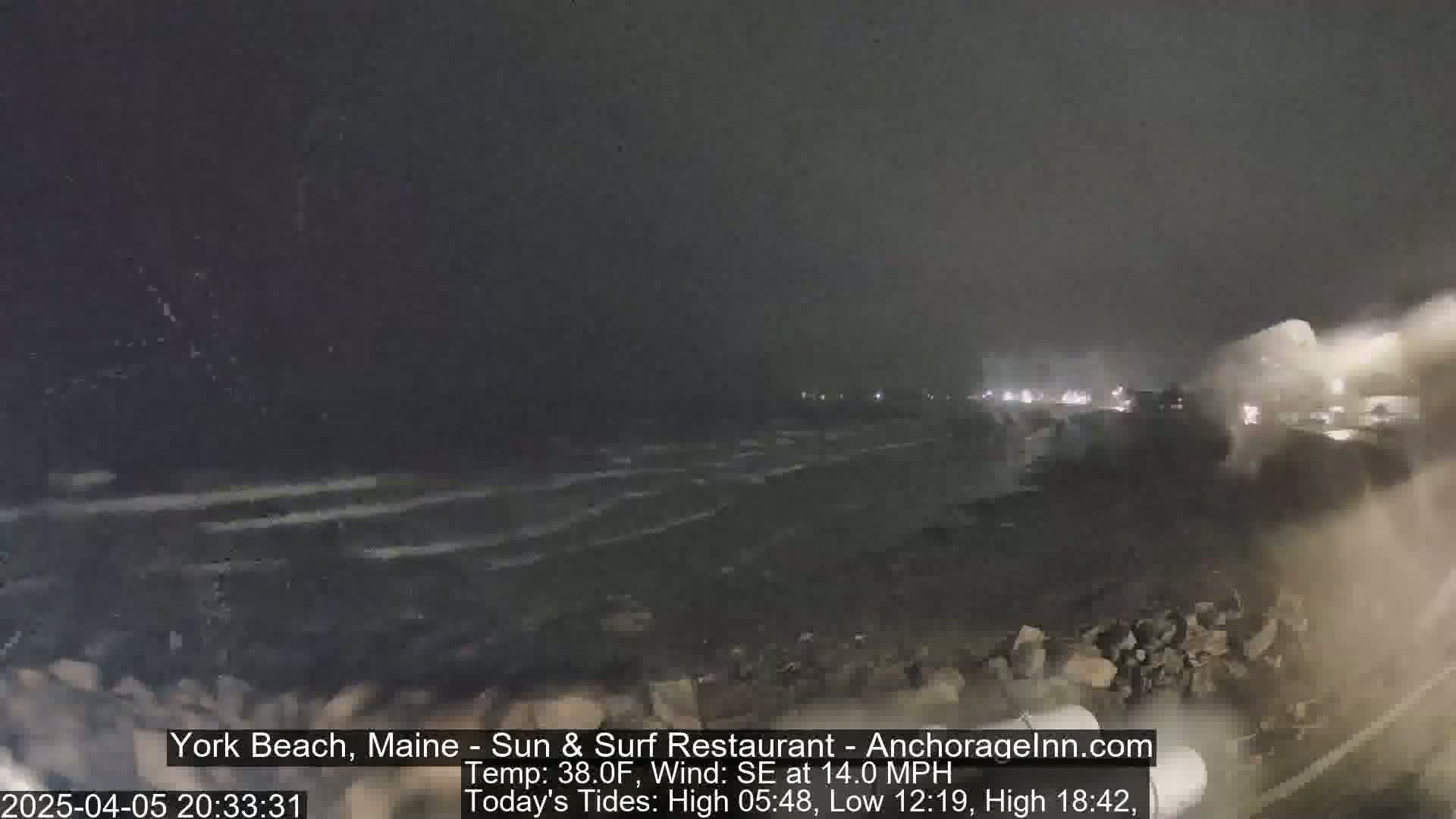 A nighttime beach scene shows dark, choppy waves under a cloudy sky with a 14 mph southeasterly wind.