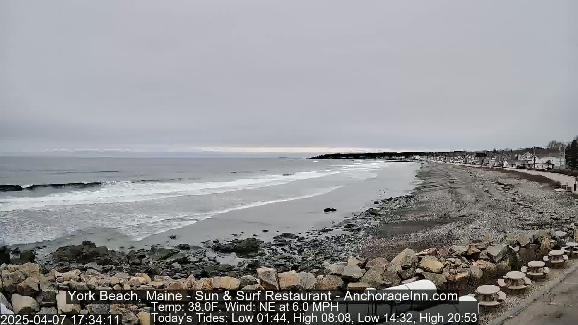A rocky beach with a calm, gray ocean stretches out under an overcast sky.