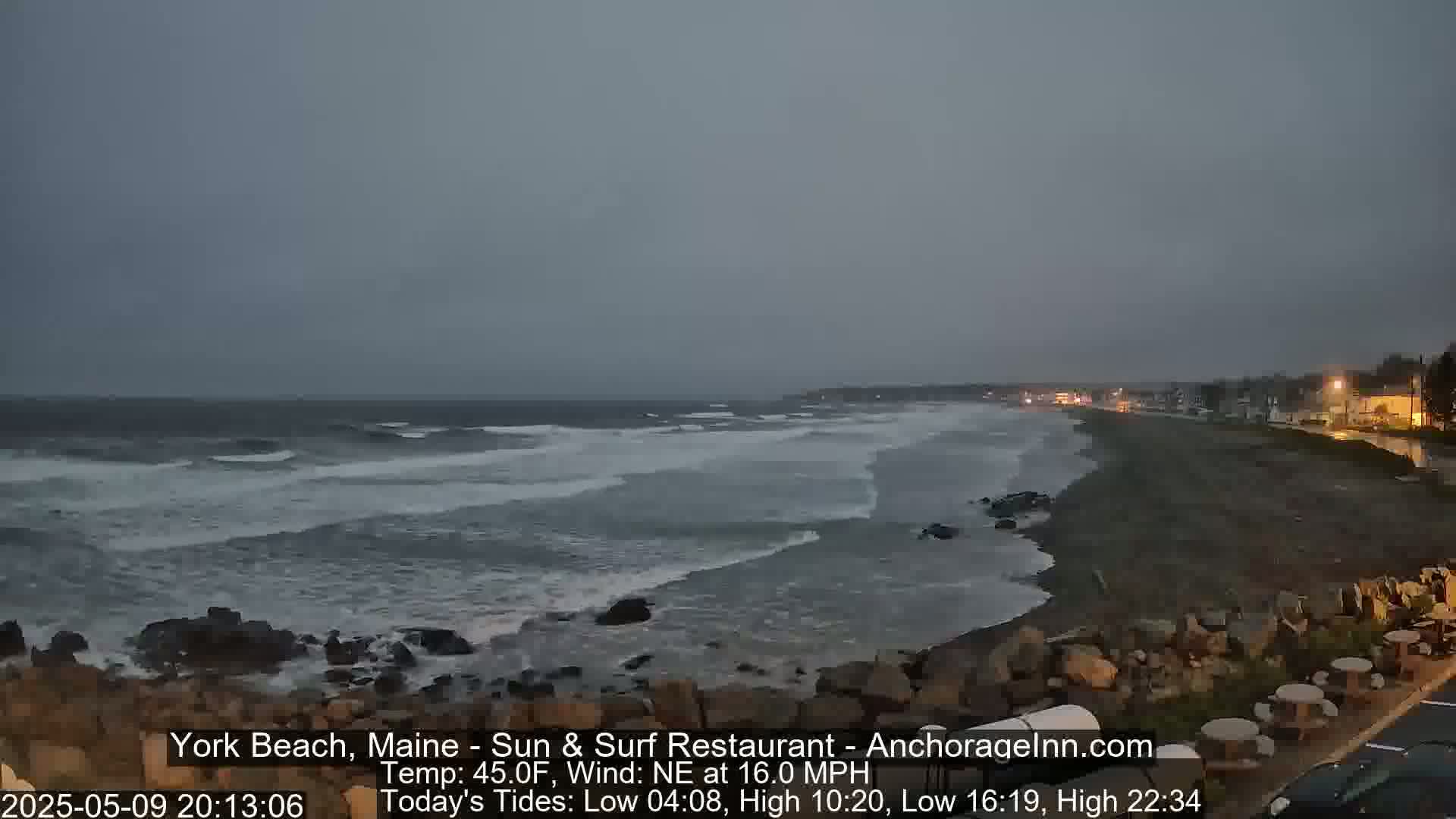 A rocky shoreline with dark, choppy waves under a gray, overcast sky.