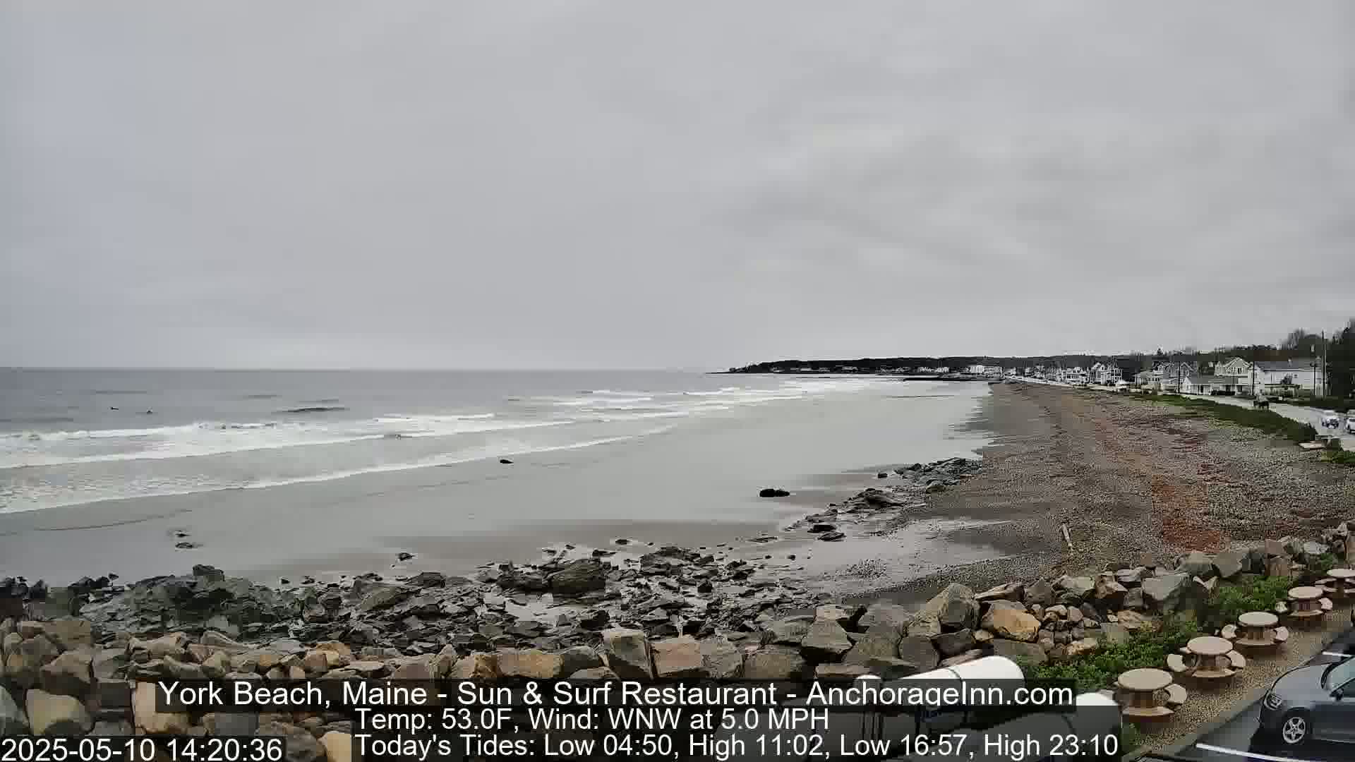 A rocky beach with a calm, gray ocean under an overcast sky.