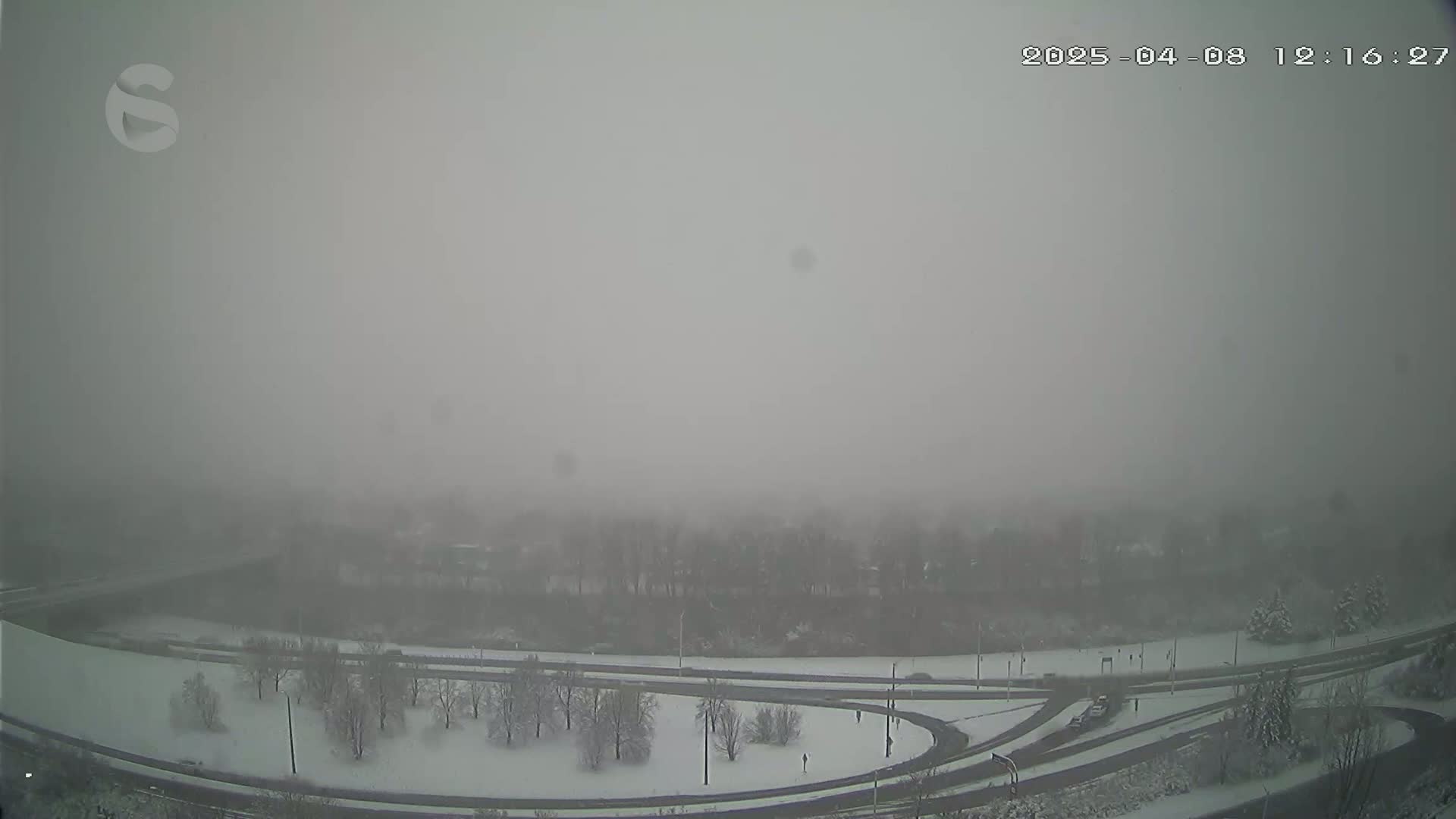 A snow-covered highway interchange is visible through a heavy fog.