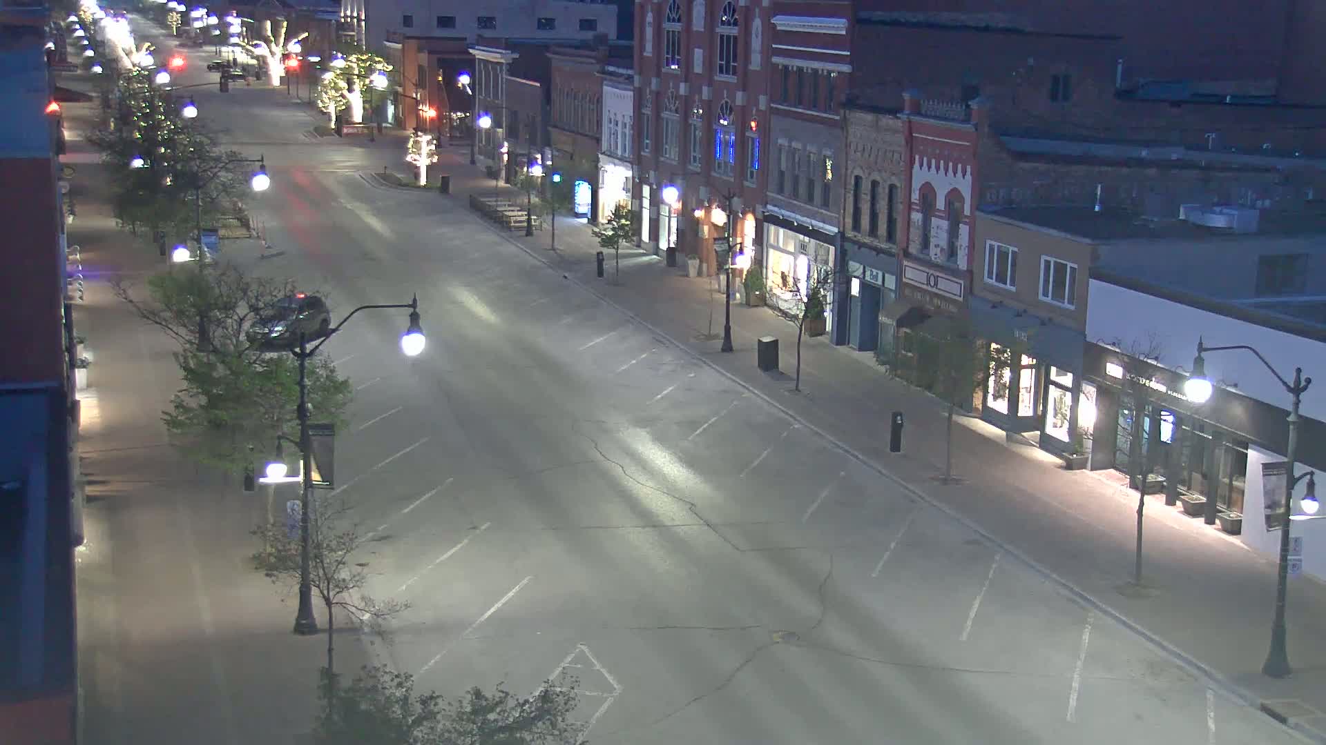 A mostly empty street lined with brick buildings at night, lit by streetlights.