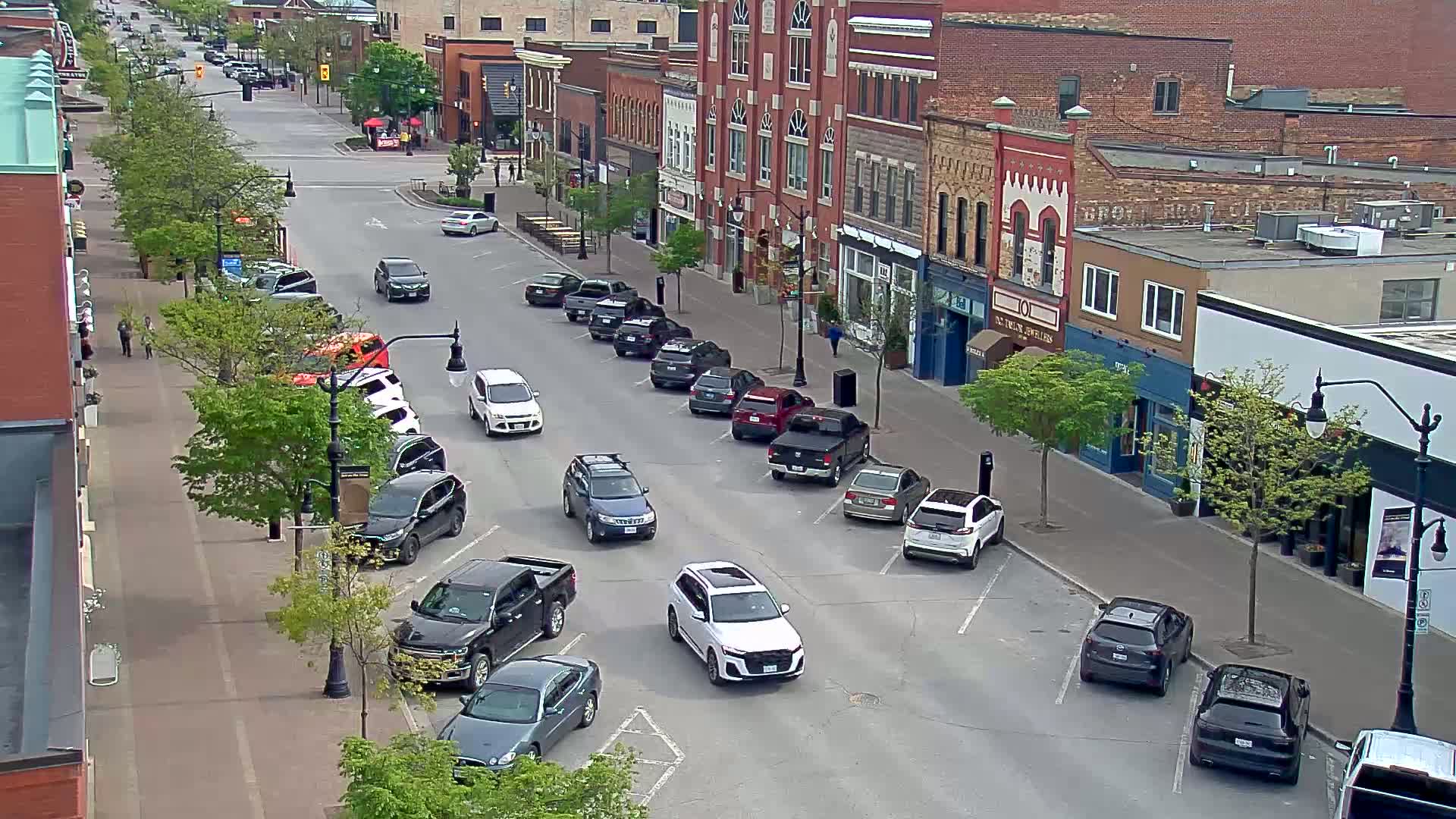 A street lined with brick buildings and parked cars on a sunny day.