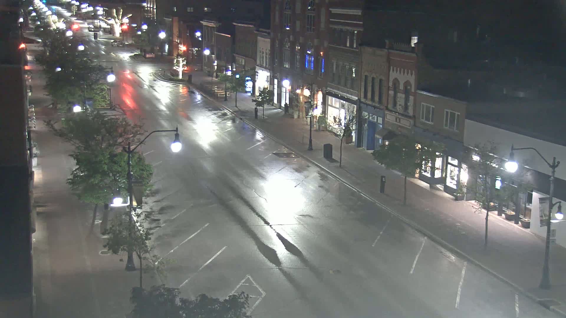 A wet, empty street at night lined with buildings and streetlights.