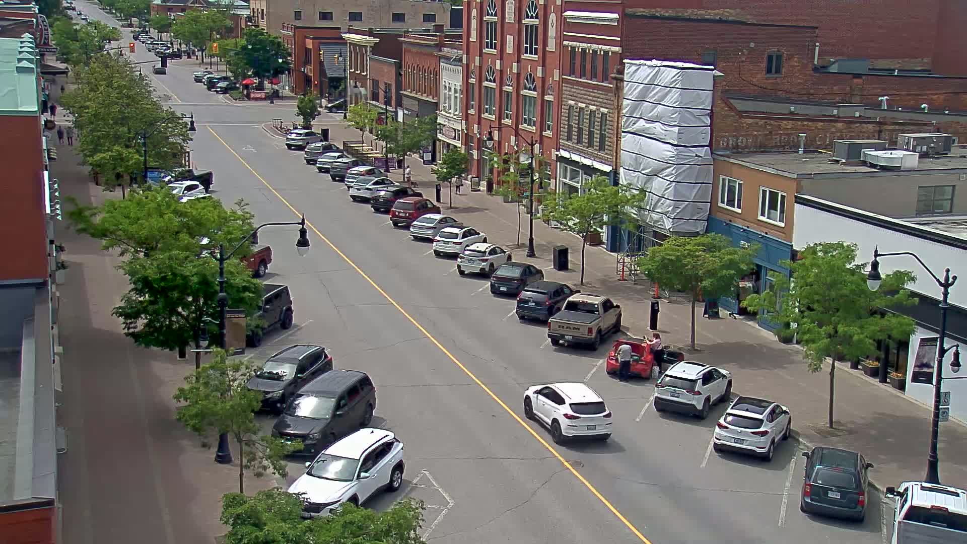 A street lined with parked cars and brick buildings on a sunny day.